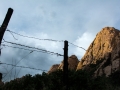 The 700-foot-tall Sheepshead looms behind a barbed wire fence in the west Cochise Stronghold outside of Tombstone, Ariz. on Saturday, Sept. 10, 2016. The fence serves to separate the  open range, where ranchers allow cattle to graze, from the rockier terrain that characterizes much of the Stronghold. (Alex McIntyre / Arizona Sonora News Service)